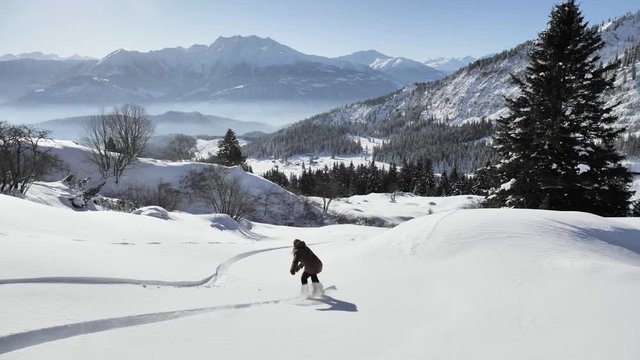 A girl is snowboarding in the backcountry during the winter in Swiss Alps. Shot in 4k with a gimbal.