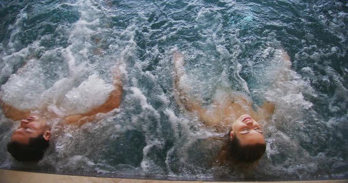 An young couple is enjoying and having relax in a whirlpool bath tube in a luxury wellness center.