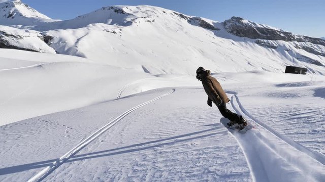 A girl is snowboarding in the backcountry during the winter in Swiss Alps. Shot in 4k with a gimbal.