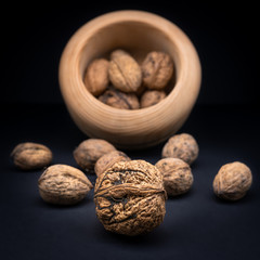 Walnuts in shell in a wooden bowl isolated on black gradient background. 