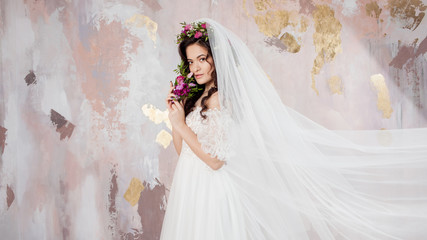 Beautiful young bride in wedding dress with veil on her face