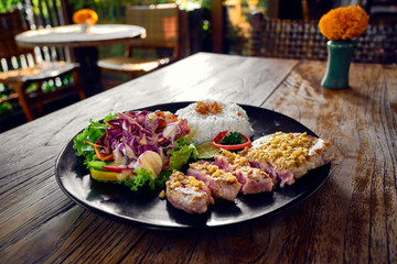 Grilled tuna steak with rice and vegetables in interior of a cafe.