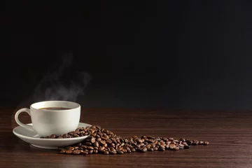 Photo sur Plexiglas Café white cup of hot coffee with smoke with coffee beans and on black background