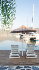 Two sun loungers and a straw umbrella from the sun, a romantic holiday on the beach. The story format
