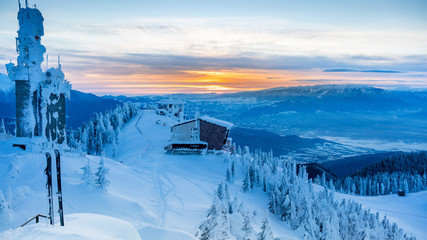 Poiana Brasov, Romania. Postavarul Peak. The top of a ski slope with sunset in the background.