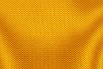 Chrome yellow background from a textile material with pattern, closeup. Structure of mikado yellow fabric with punching texture. Perforated cloth backdrop.