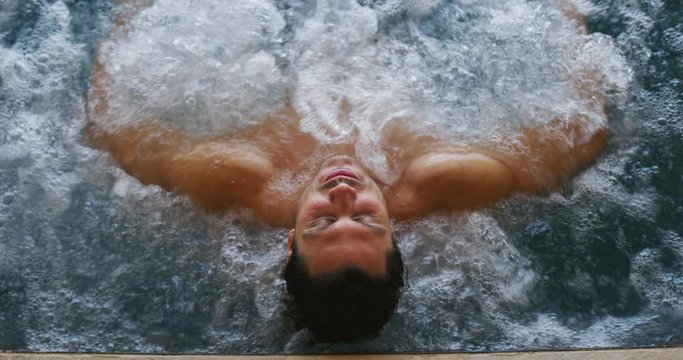 Portrait of an young man is enjoying and having relax in a whirlpool bath tube in a luxury wellness center.
