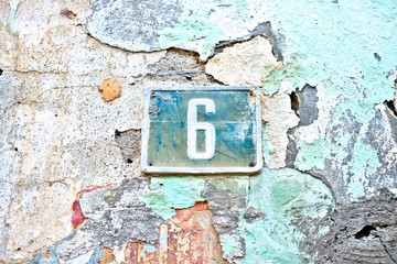 Number 6, six, vintage blue plate on a beautiful wethered wall with flaking plaster and old pastel paints.
