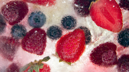 different juicy berries frozen in ice. useful vitamin healthy food