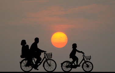 Obraz premium silhouette happy family ride bike on sunrise