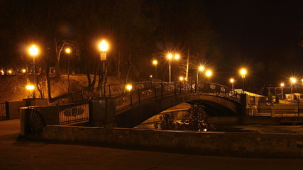 Smolensk, Russia, Gorbaty Bridge on Pond with glowing orange streetlight, beautiful autumn night in Park Lopatin Garden