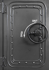 Black metallic background with rivets. Safe with round circle door handle.  Metal texture with copy space.