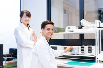 実験室で研究開発・解析・調査をする白衣の男性と女性（カメラ目線）
