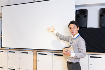 スクリーンの前でプレゼンテーションをする男性