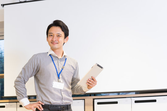 スクリーンの前でプレゼンテーションをする男性