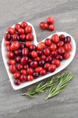 Fresh red cranberries on a heart shaped plate with rosemary. Heart Healthy Concept.