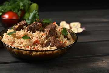 Oriental cuisine.  Pilaf with meat on a wooden table.	