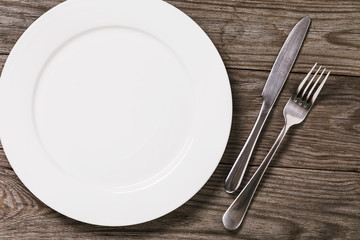 Empty plate and cutlery on a wooden table with copy space, top view. Food background
