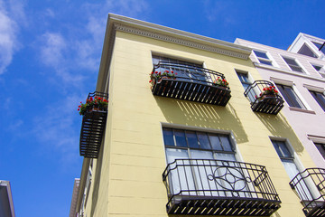Fototapeta na wymiar Yellow Building with Wrought Iron Balcony and Shadows with Blue Sky