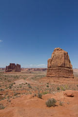 Fototapeta na wymiar Tall Red Rock Formations in Desert Under Blue Sky