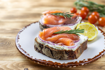 Sandwich with smoked salmon, tomatoes, soft cheese, fresh rosemary. Healthy nutrition. Concept for healthy snack. Close up.