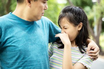 Foul-smelling man was hugging her daughter while her child girl can smell the armpit smelly or the body odor foul from her father with closing her nose,feel stinks,asian male sweat from hot weather - obrazy, fototapety, plakaty