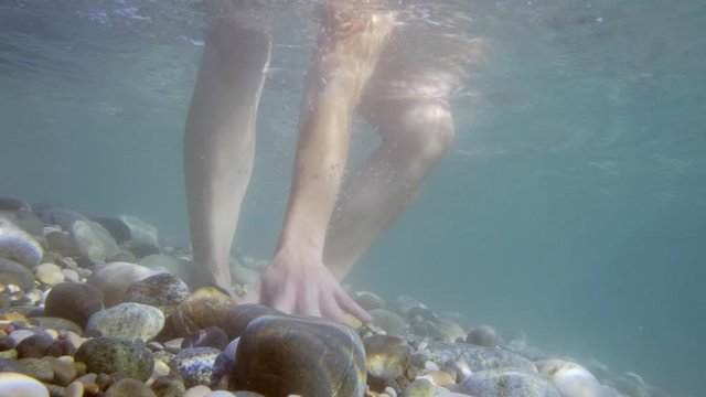 phone falls into water at bottom of sea. woman is trying to catch smartphone underwater.