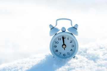 Small alarm clock in snow with copy space for your text.