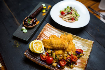 crispy fried fish served with fried aubergine and fresh tomato salad