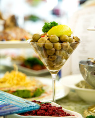 green olive pickles served in martini glass topped with lemon and herbs