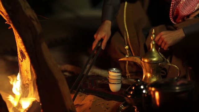 Riyadh, Saudi Arabia 19-07-2018 : A Bedouin Man making Coffee on wood next to fire place in desert night time beauty shot
