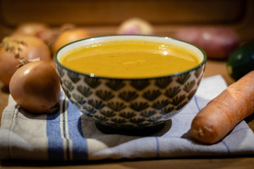 Bowl of vegetable soup with Vegetables around on wooden Background