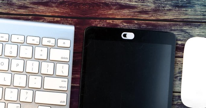 White Camera Privacy Cover. Slide Webcam. Cover for an electronic device with keyboard and mouse on a colourful dark wooden table
