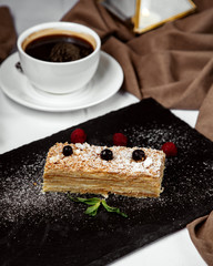 napoleon cake piece garnished with sugar powder, served with black tea