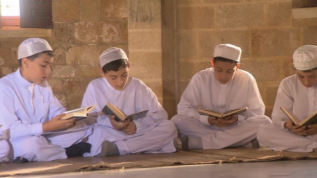 An old Muslim reads Quran, group of young Muslims read Quran, inside a mosque