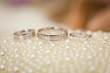 wedding rings on white pearl background