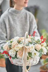 Flower arrangement in Wicker basket. Beautiful bouquet of mixed flowers in woman hand. Floral shop...
