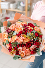 Red tones Beautiful bouquet of mixed flowers in womans hands. the work of the florist at a flower shop. Handsome fresh bouquet. Flowers delivery