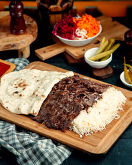 beef kebab served with rice and flatbread placed on wood serving board