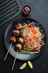 Black plate with vietnamese nem nuong and pho noodles, vertical shot over black stone background, flatlay
