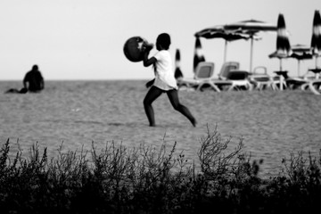 The boy plays a ball on a beach; blurred  black and white photo