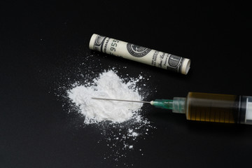 Cocaine or other illegal drugs, white powder, syringe, isolated on black glossy background