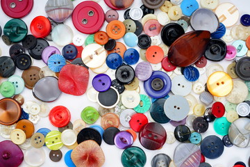Many different buttons on a light background. Selective focus. Home needlework