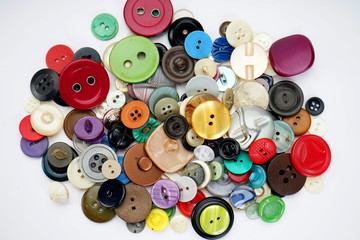 Many different buttons on a light background. Selective focus. Home needlework