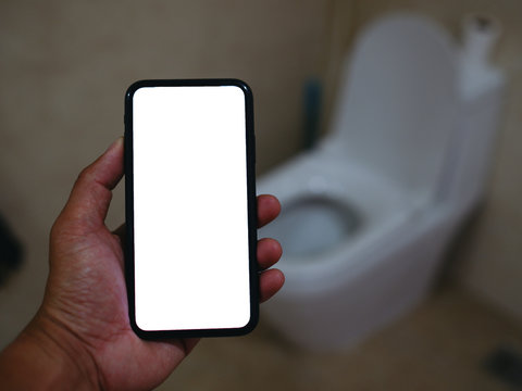 Smart phone with white screen background in toilet, restroom or WC. Closeup of hands using mobile phone with blank copy space screen, empty white screen for advertising text in toilet, restroom or WC