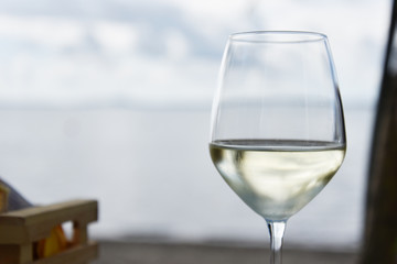 A glass of white wine with lake or sea on the background
