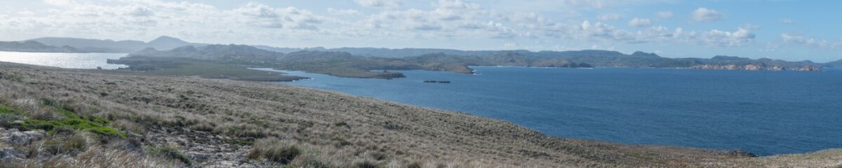 Fototapeta na wymiar Côte rocheuse et îlot à proximité du cap et du phare de Cavallería, en arrière-plan le mont El Toro, Minorque, îles Baléares