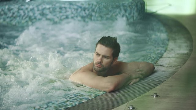 Handsome man resting in jacuzzi spa. Sexy man relaxing in whirlpool bath