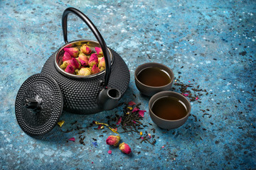 Black japanese cast iron teapot with tea and dry roses