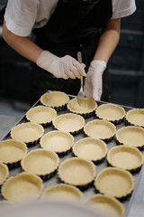 Shortcrust tartlets on a baking sheet. Cooking in the kitchen in a restaurant or bakery. The chef creates a delicious dessert for the coffee shop.